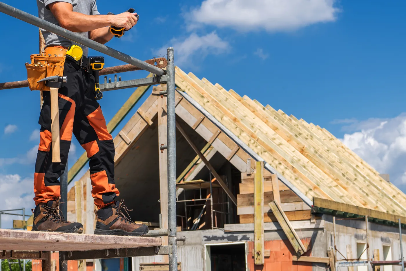 Builder on scaffolding beside a new timber roof structure
