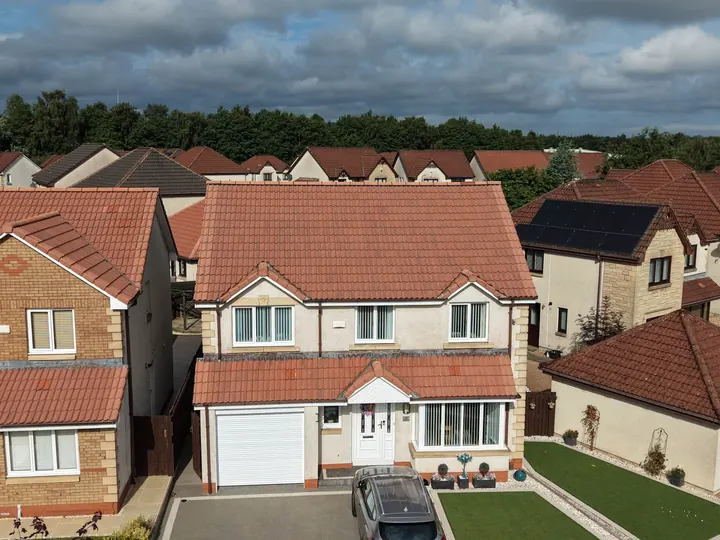 Large detached house with a newly finished red tiled roof from the air