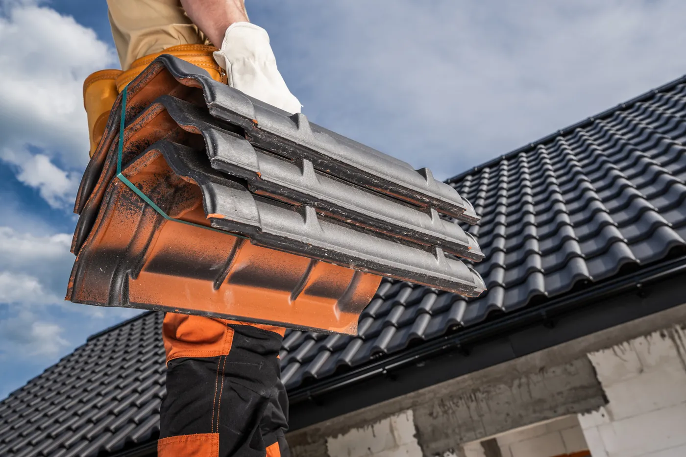 Roofer carrying a stack of roof tiles up to a pitched roof
