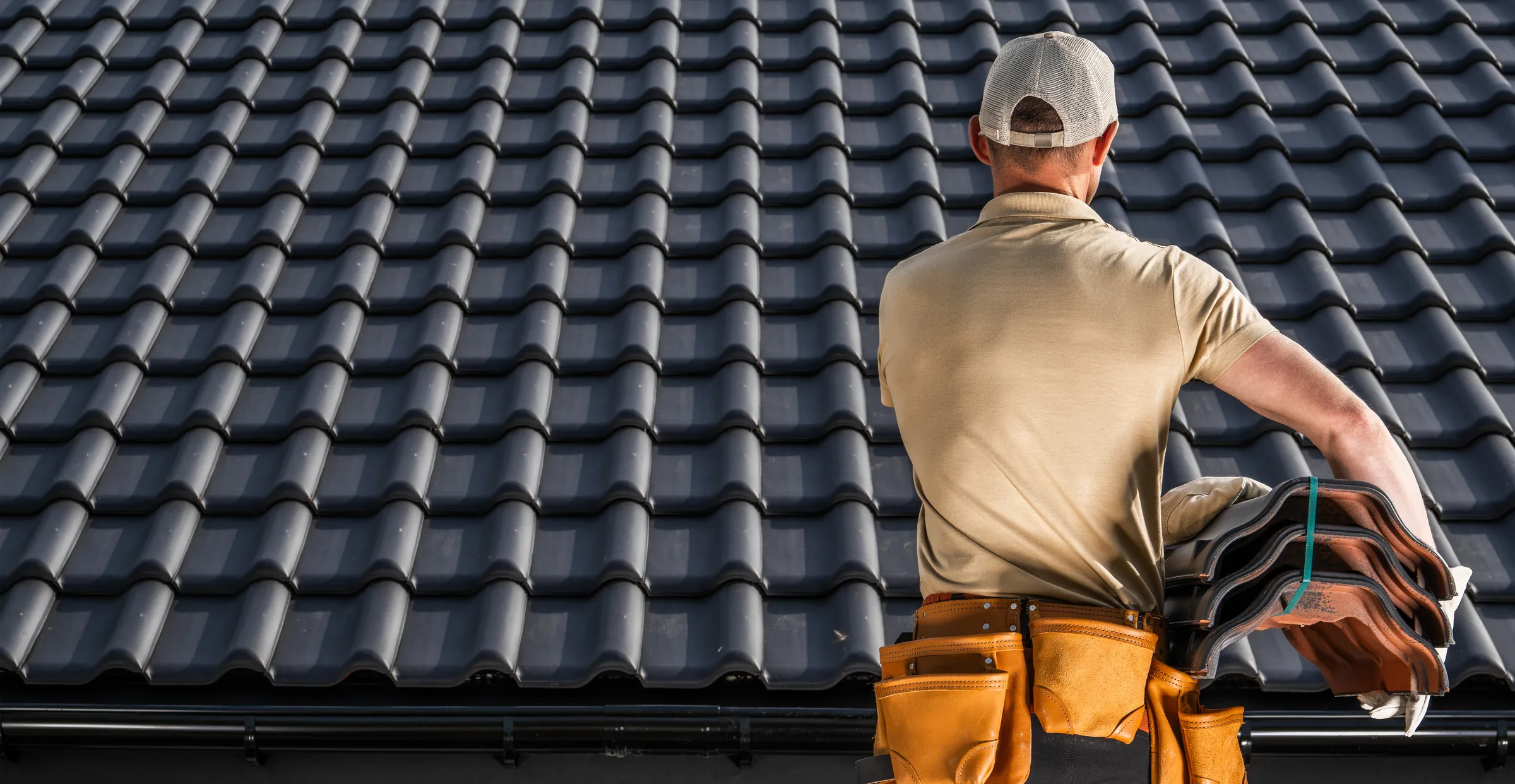 Roofer carrying a stack of tiles across a tiled roof