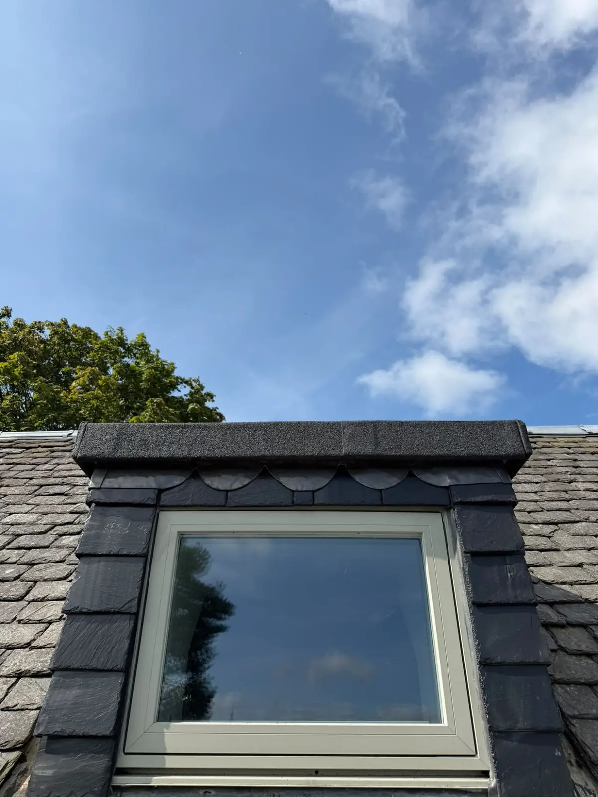Slate-clad dormer window with a decorative scalloped slate course