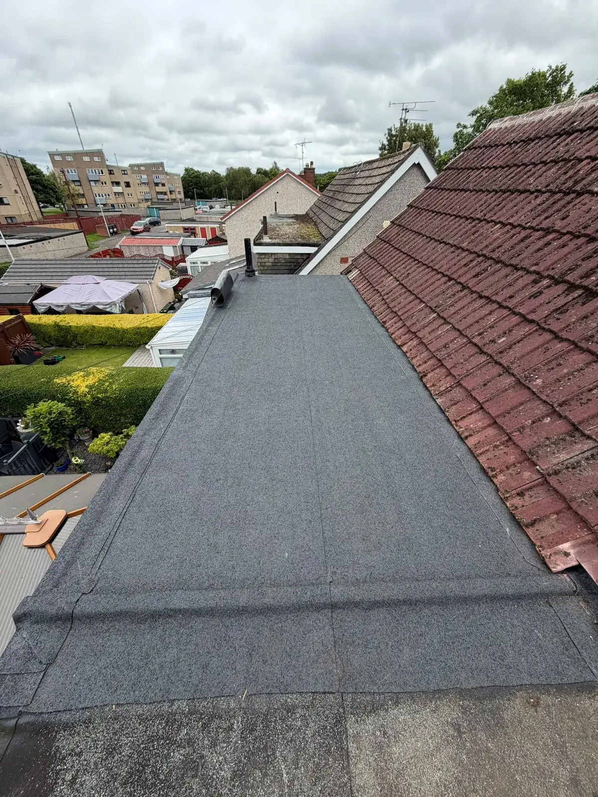 Torch-on felt flat roof running alongside a tiled pitched roof